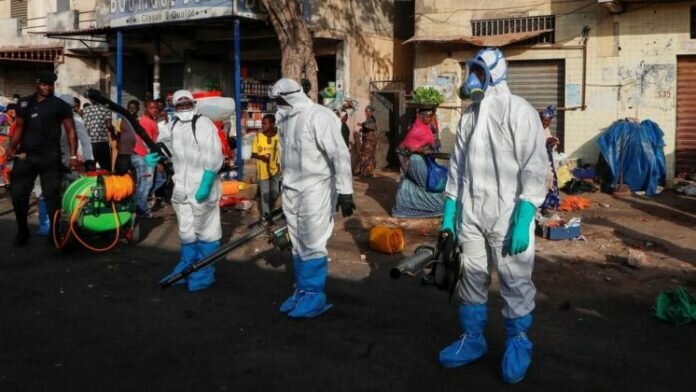 Des membres des services de santé et d'hygiène sénégalais se préparent à désinfecter les rues d'un marché de Dakar afin de lutter contre le coronavirus, le 22 mars 2020